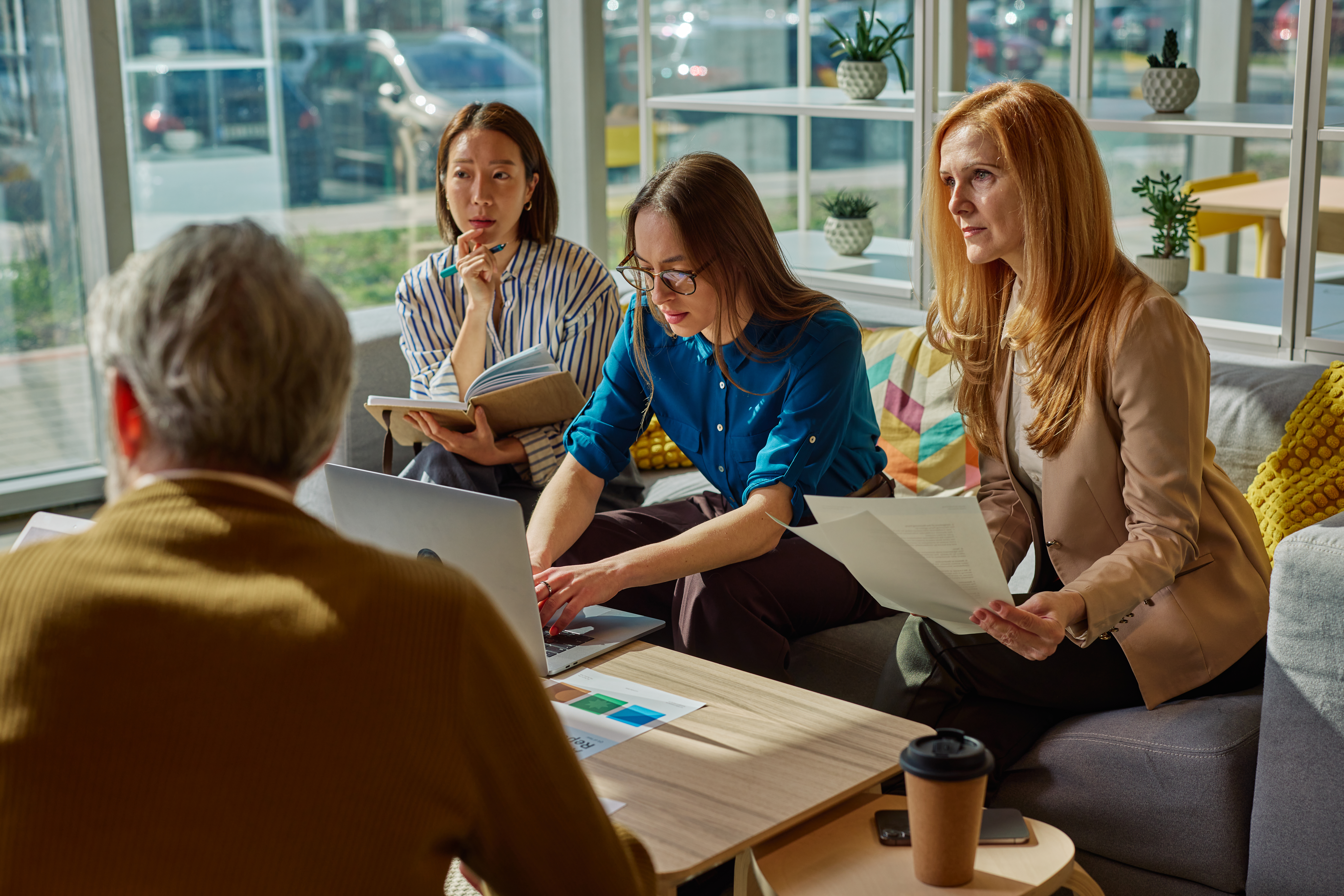 Diverse business team discussing strategy and working together on a laptop during a meeting in a contemporary workspace